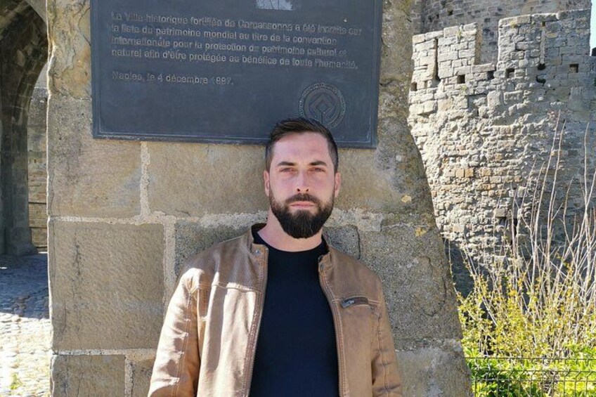 Un homme se tient devant un mur de pierre orné d’une plaque. 4