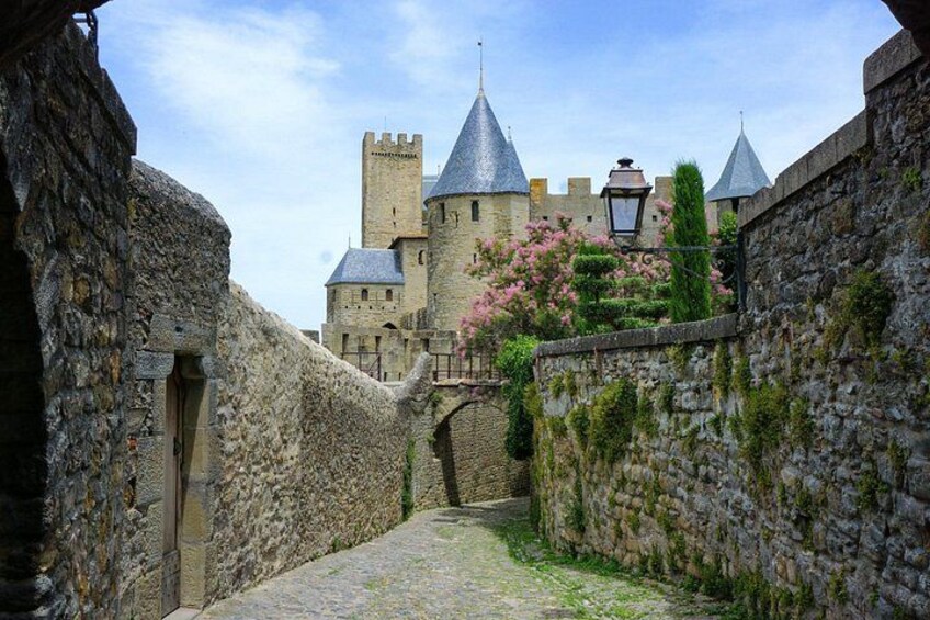 Un sentier de pierre d’époque médiévale menant à un château doté d’une tour et d’un mur couvert de fleurs. 5