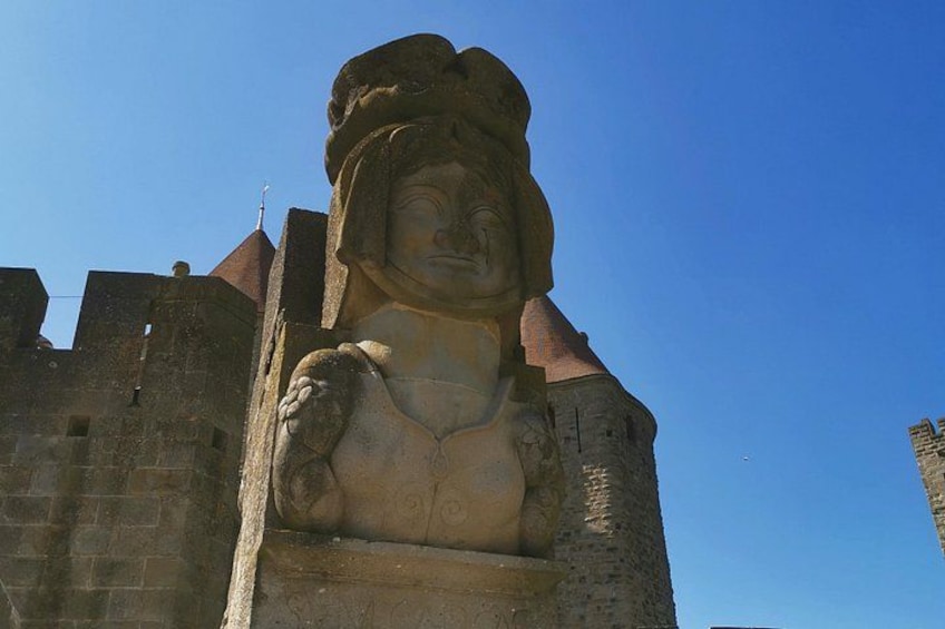 Une grande statue de pierre représentant une femme portant une couronne, se détachant sur un ciel bleu clair. 2