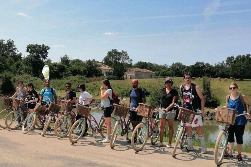 Un grupo de personas en bicicletas con cestas, de pie junto a un cuerpo de agua. 2