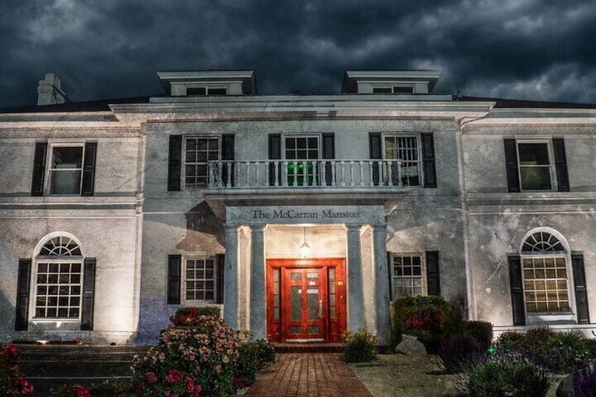 The McCarran Mansion with a red door, surrounded by a garden with flowers and a brick pathway. 3