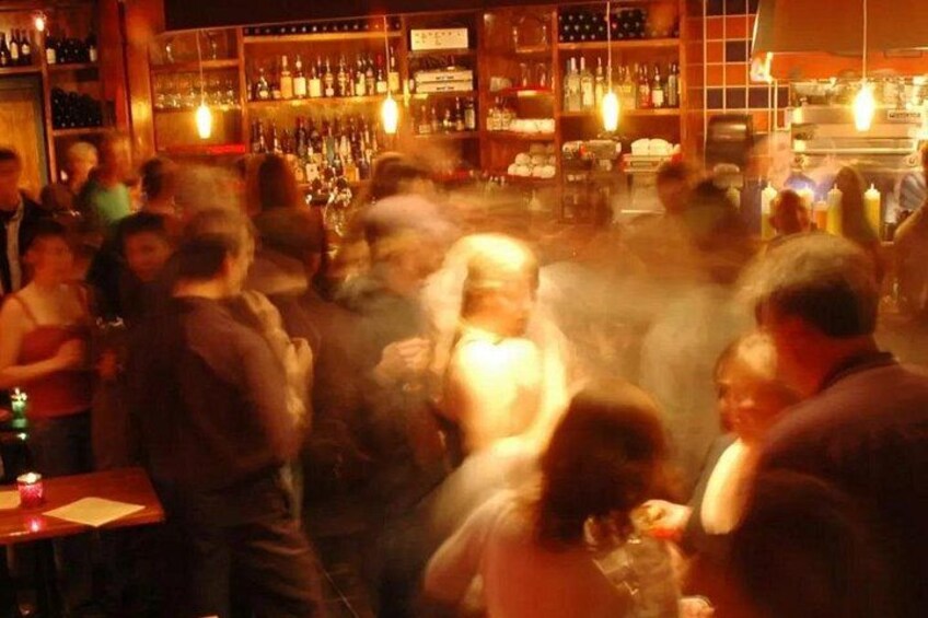 A crowded bar with people standing and socializing. 4