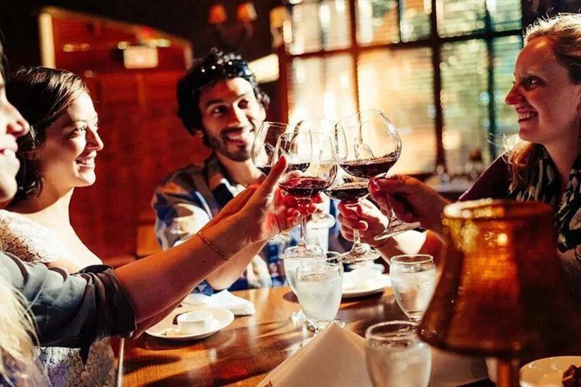 A group of people toasting with wine glasses at a table with a candle in the background. 2