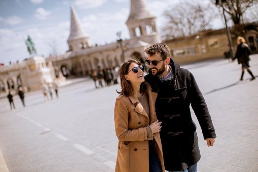 A couple standing in a public square with historical architecture in the background. 3