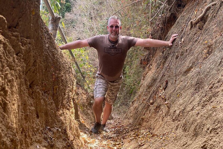 A person hiking through a narrow, rocky trail surrounded by trees. 3