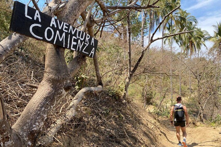 Ein Wanderer auf einem Pfad, an dem ein Schild mit der Aufschrift 'LA AVENTURA COMIENZA' steht. 3
