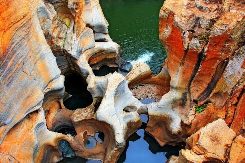 A rock formation with multiple caves and a body of water. 2