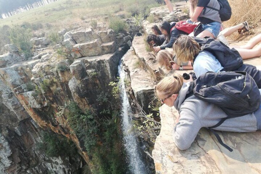 A group of people observing a narrow water channel between rocky cliffs. 5