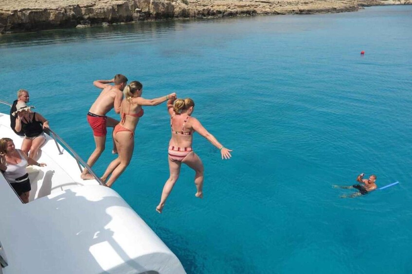 A group of people jumping off a boat into a clear blue sea. 5