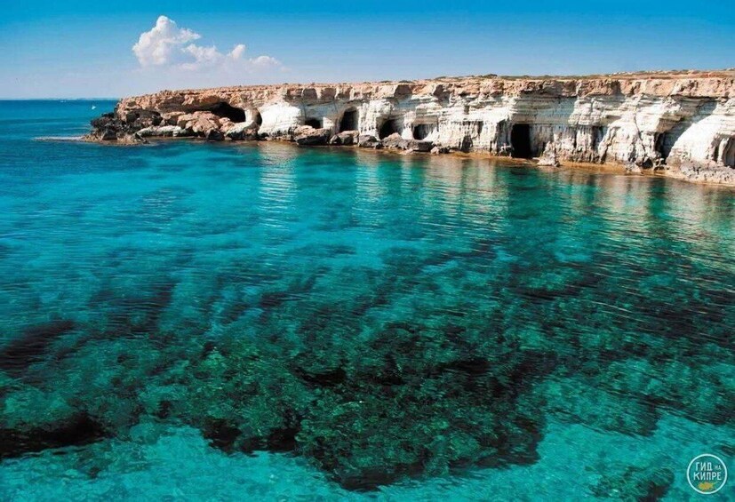 A coastal cliff with caves and clear turquoise water. 5