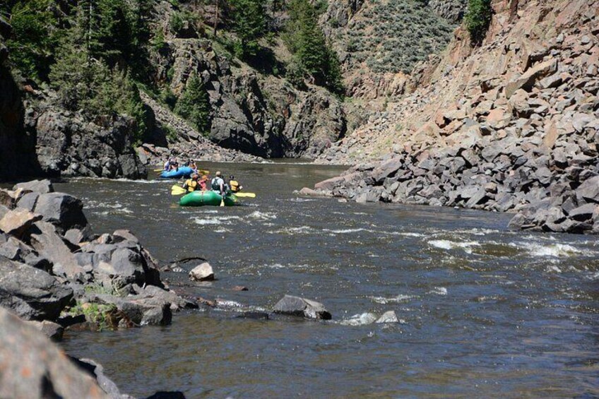 A river with people rafting in a green raft. 3