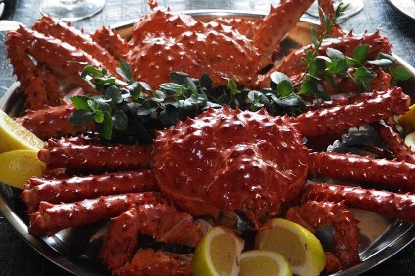 A platter of cooked crab legs garnished with lemon slices and herbs. 3