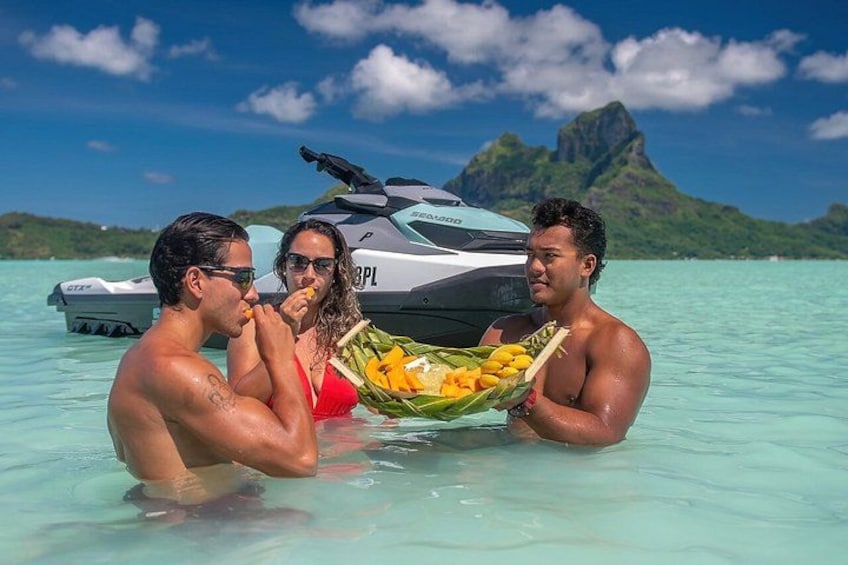 Drie mensen in een boot, een jetski en een bergachtig landschap op de achtergrond. 2