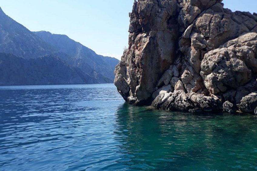 A rocky coastline with clear blue water and mountains in the background. 4