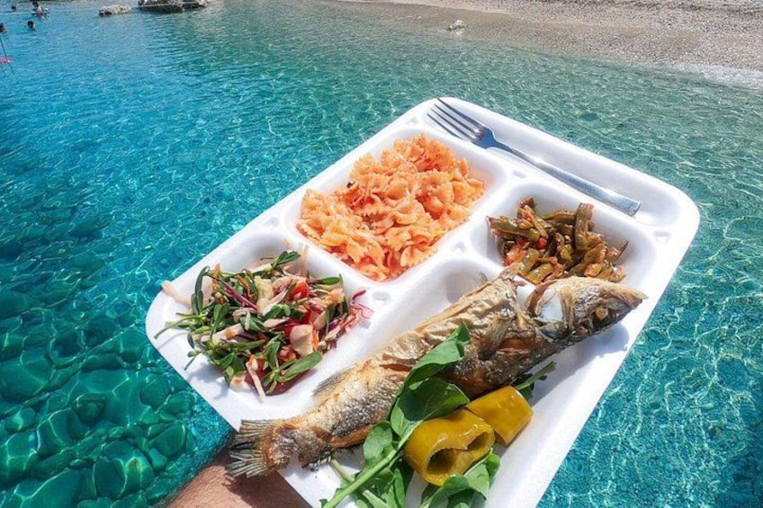 A tray with food and a fish on a beach. 2