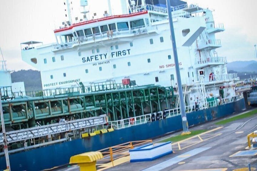 Un'ampia nave bianca, chiamata 'SAFETY FIRST', ormeggiata in un porto con un cartello 'NO SMOKING' e un avviso 'PROTECT ENVIRONMENT'. 3