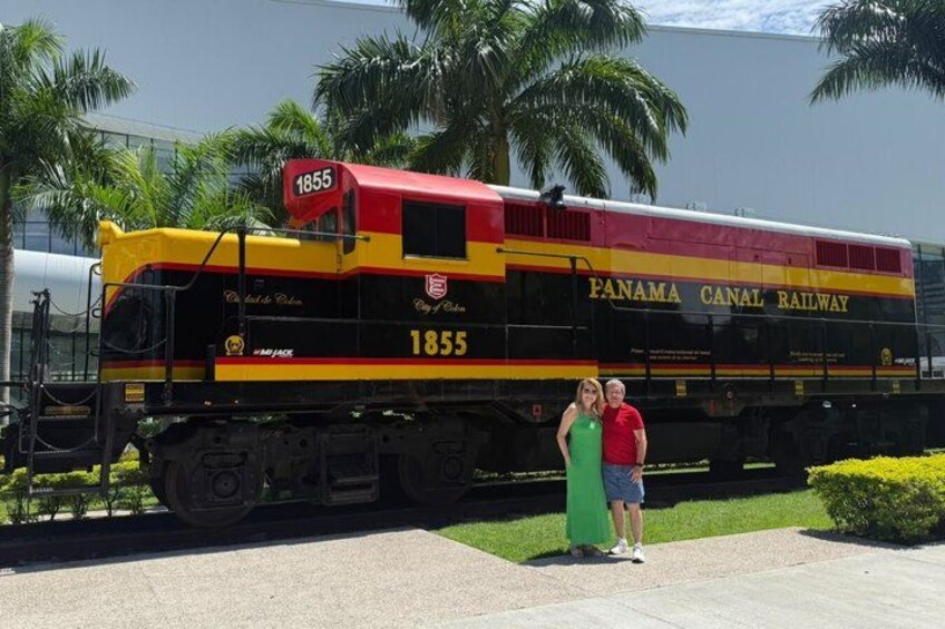 A Panama Canal Railway train numbered 1855, with two people standing in front of it. 2