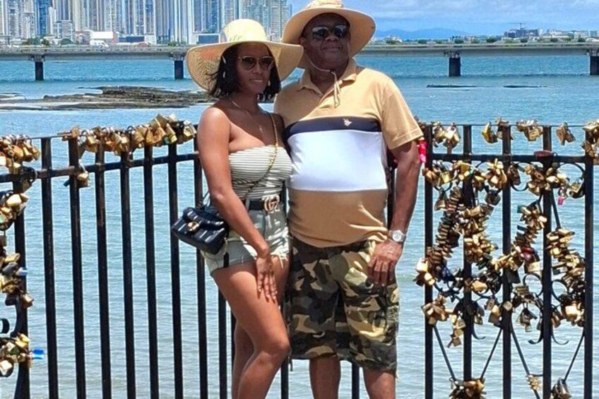 A couple standing by a waterfront with a bridge in the background. 4