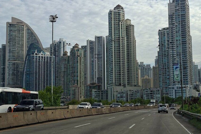 A cityscape with tall buildings, a highway, and a bus. 5