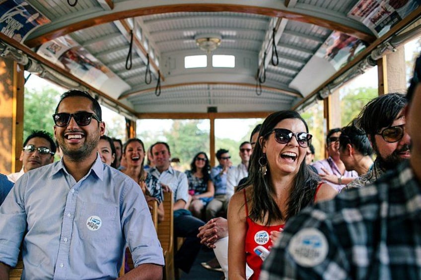 A group of people on a covered bus with a curved roof, some wearing lanyards. 2