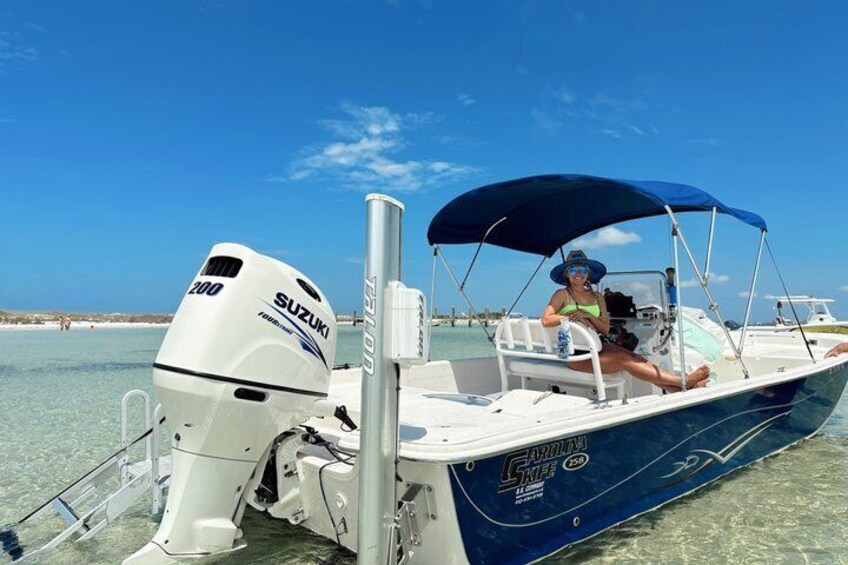 A blue boat with a Suzuki outboard motor, a canopy, and a person wearing a hat and sunglasses. 1