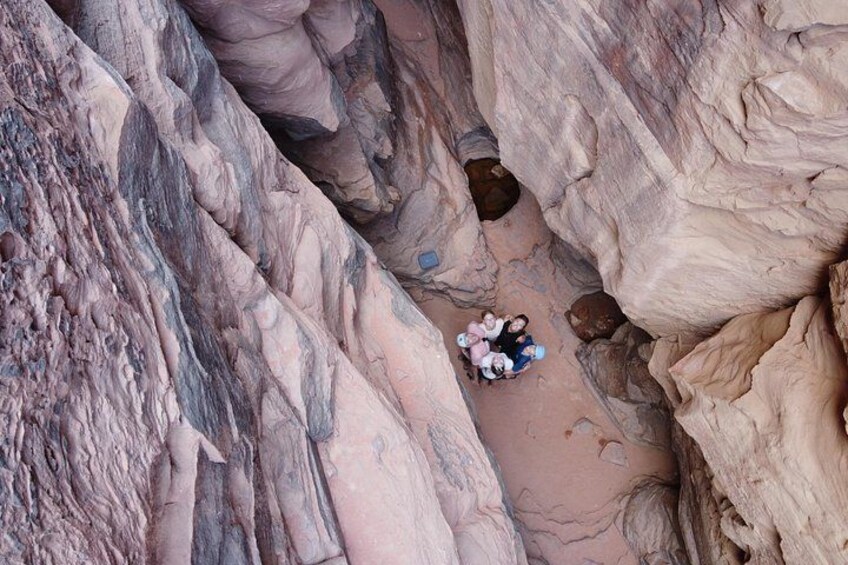 A narrow canyon with large rock formations and a small group of people sitting on the ground. 5