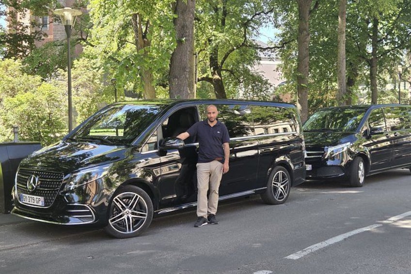 A black Mercedes-Benz van parked on a street with trees and a lamp post in the background. 2