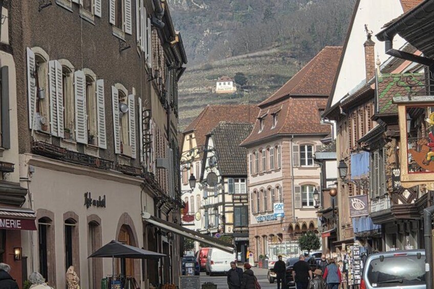 A street with buildings, a mountain in the background, and a car. 2
