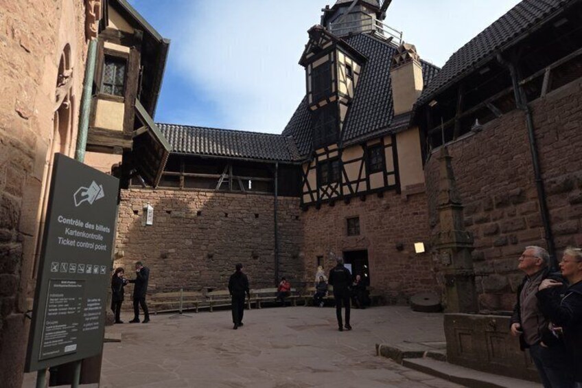 Un edificio histórico con un punto de control de entradas, un muro de piedra y una estructura tradicional de entramado de madera. 4