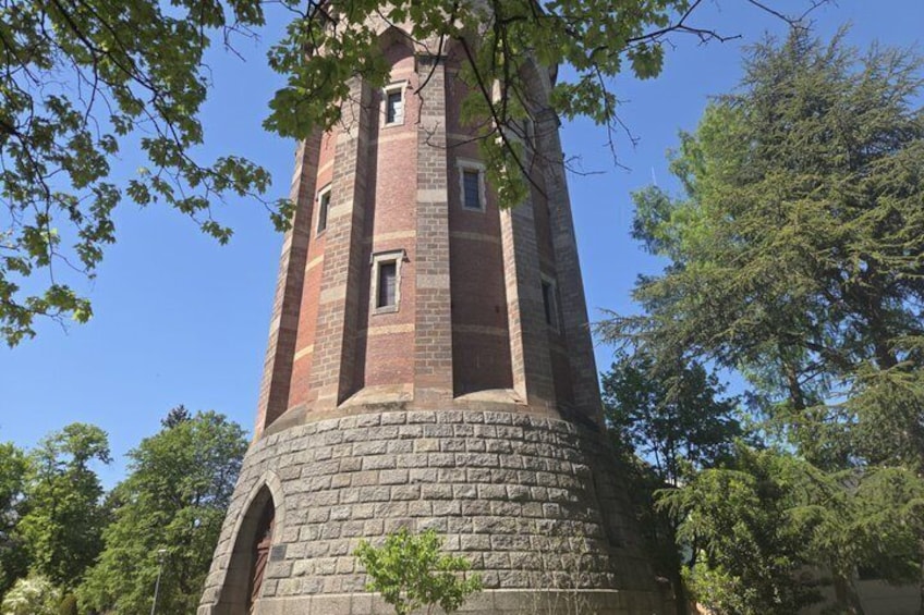Una torre de ladrillo con base de piedra, rodeada de árboles. 1