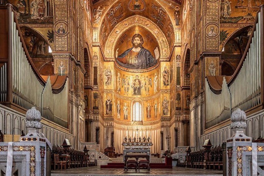 Interior de una iglesia ornamentada con un altar central, mosaicos intrincados y un gran órgano. 1