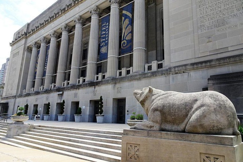 A large building with classical architecture, including columns and a statue of a bear. 1