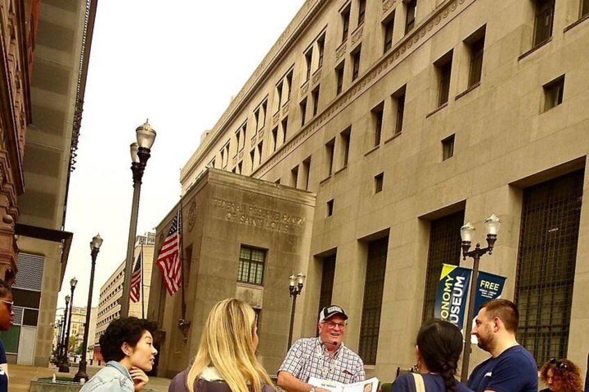 Een groep mensen staat voor een gebouw met een bord waarop staat: 'OFFICE OF THE FEDERAL RESERVE BANK OF SAN FRANCISCO'. 2