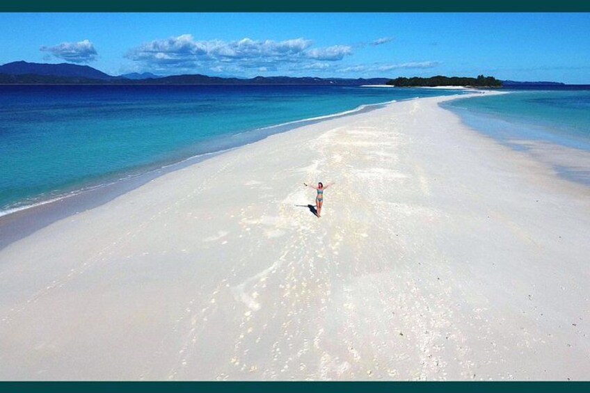 A beach with clear turquoise water and a person in a swimsuit. 2