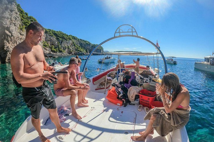 Eine Gruppe von Menschen auf einem Boot vor blauem Wasser und steinigen Klippen. 5