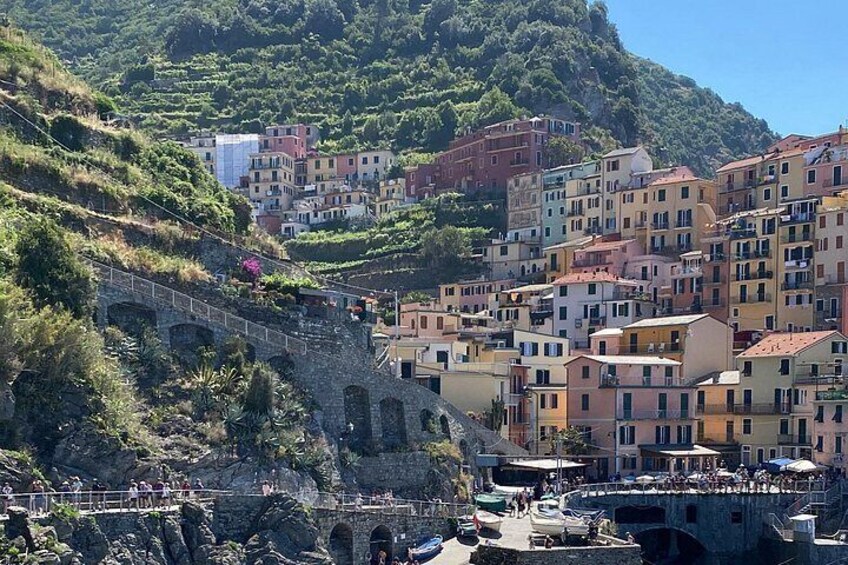 A coastal town with a stone bridge, terraced buildings, and a hillside backdrop. 3