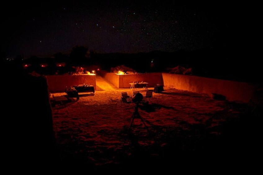 Une scène nocturne dans le désert, avec un feu de camp, une tente et un véhicule. 3
