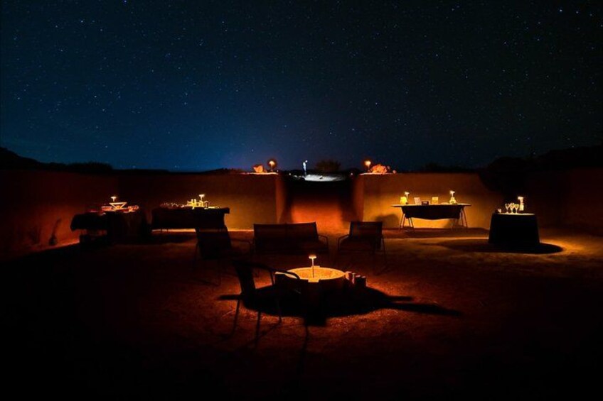 Une scène nocturne dans le désert, avec des tables et des chaises sous un ciel étoilé. 1