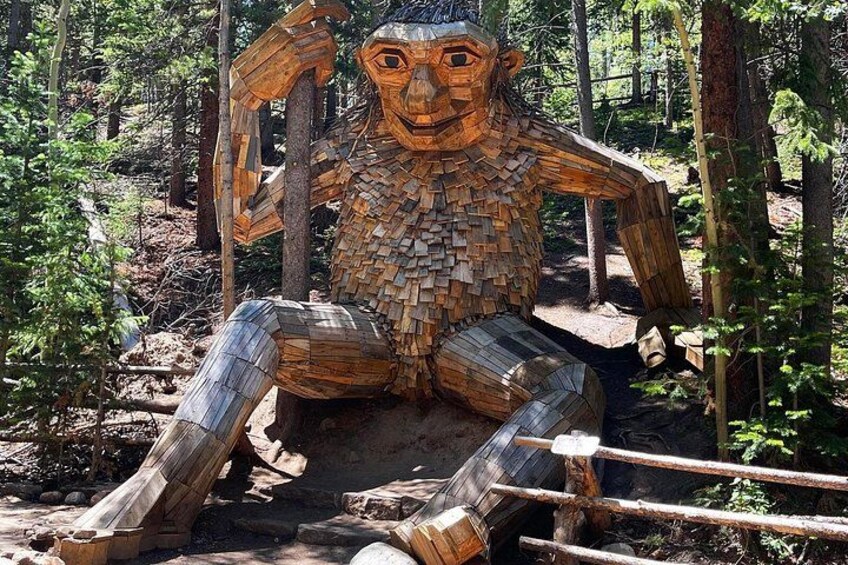 Una escultura de madera de una figura sentada en un bosque. 3