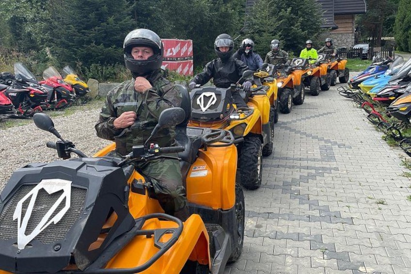 A group of people on ATVs lined up on a paved path. 1