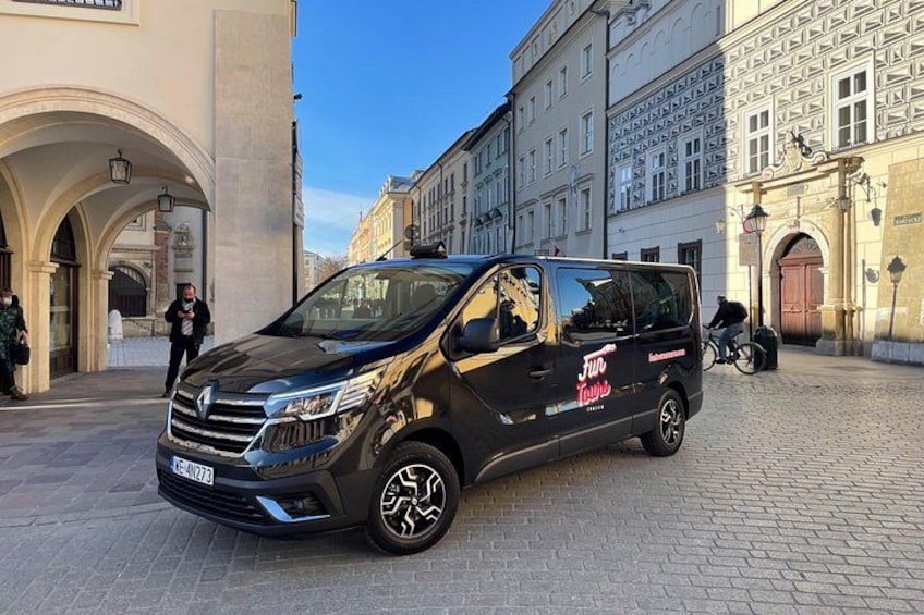 A black van parked on a cobblestone street with a building in the background. 3