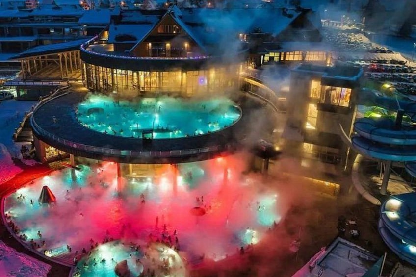 A hot spring area with a circular pool, a wooden building, and a covered walkway. 2