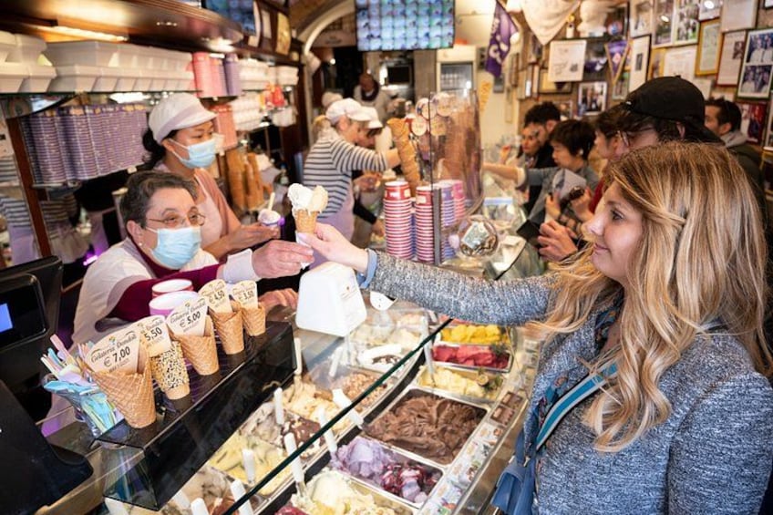 A person ordering ice cream from a vendor at a busy ice cream shop. 2
