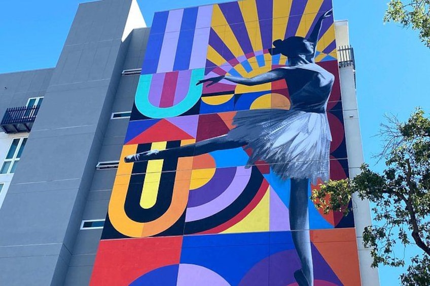 A colorful mural with a dancer and abstract shapes on a building. 2