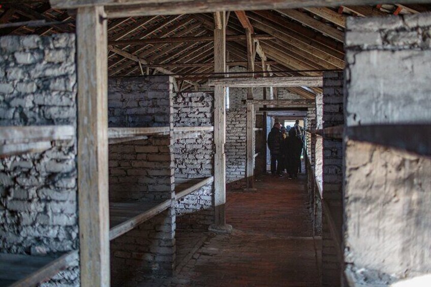 A stone-walled corridor with wooden beams and benches. 1