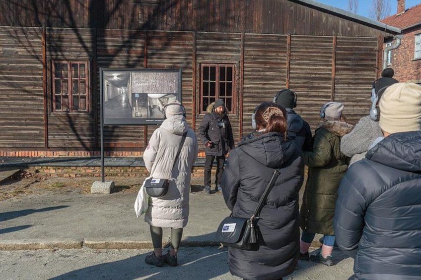 A group of people standing in front of a wooden building with a signboard. 2