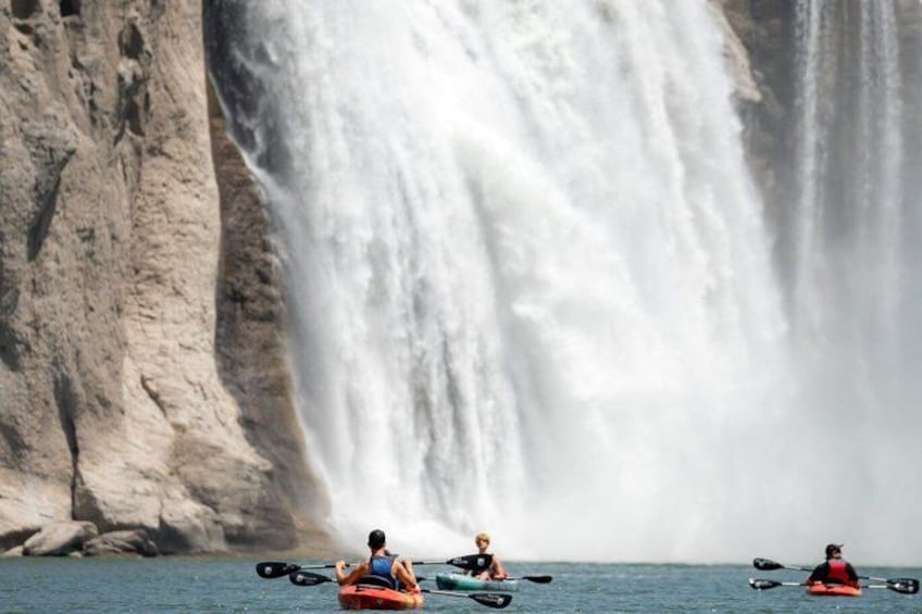 Kajakfahrer auf ruhigem Gewässer, im Hintergrund ein großer Wasserfall. 3