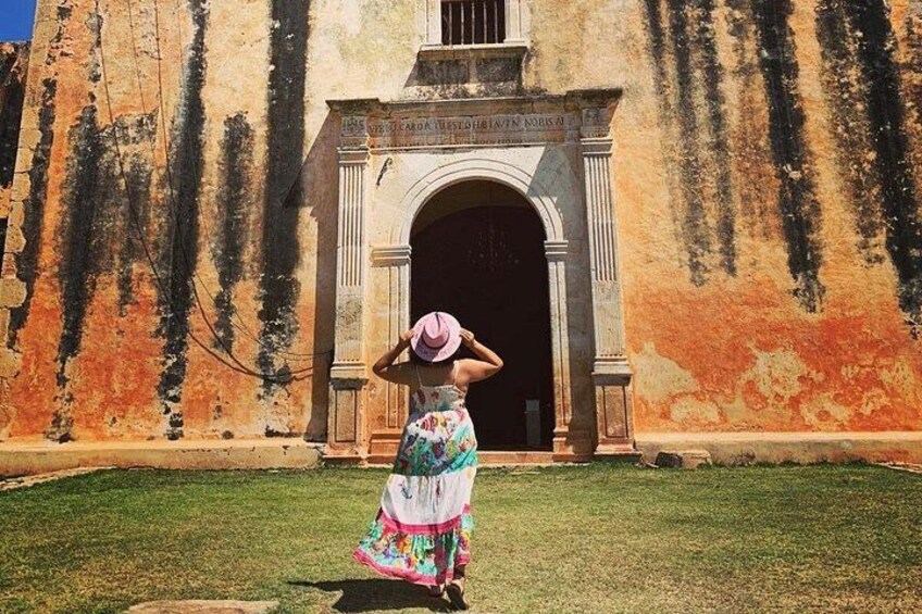 A person in a colorful dress standing in front of a historic building with an arched entrance. 3