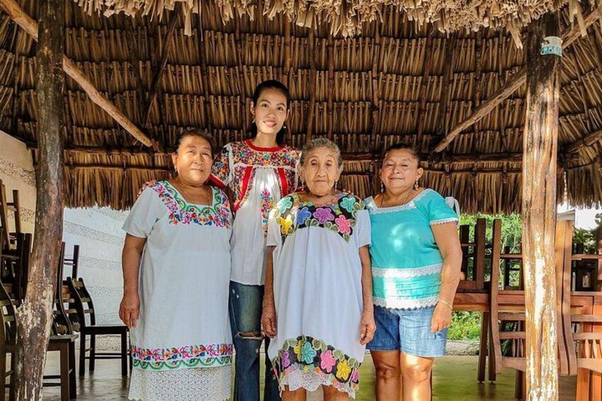 A group of people standing under a thatched roof structure. 5