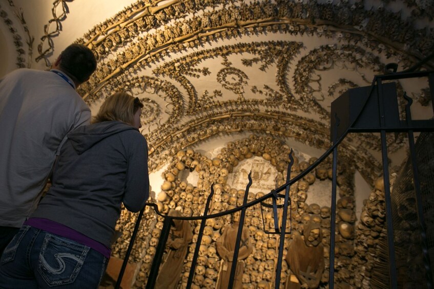 A person observing a wall with skulls and intricate carvings. 2